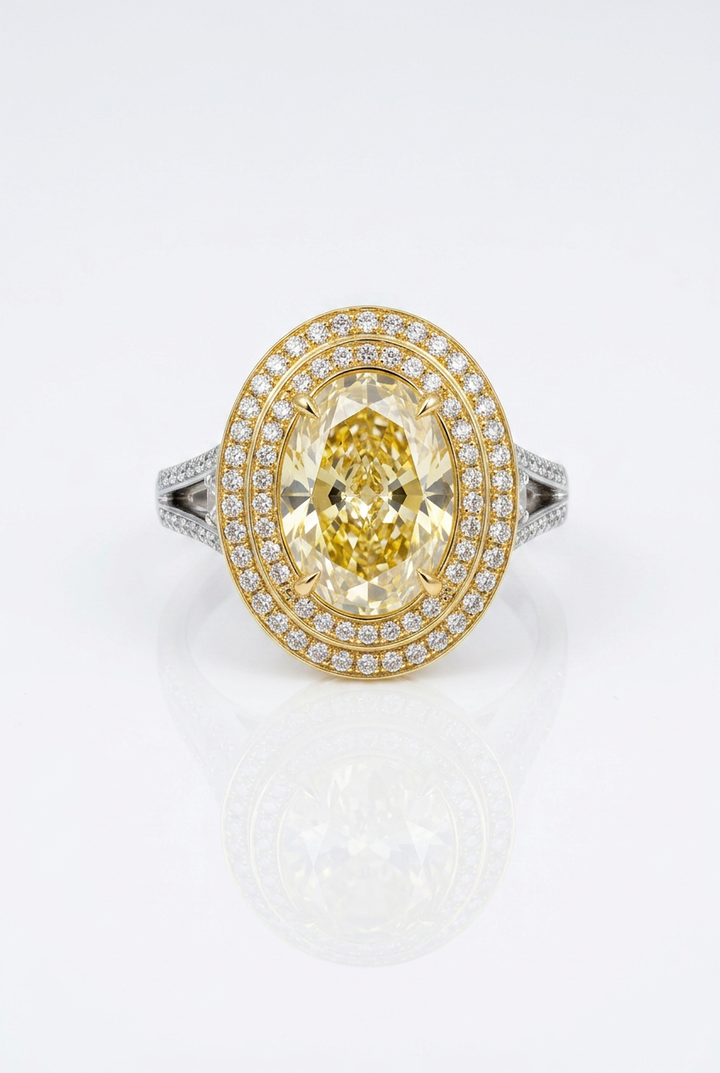Fancy Vivid Yellow oval lab-grown diamond ring with double white pavé halo on a yellow gold frame and white gold split shank — studio front view