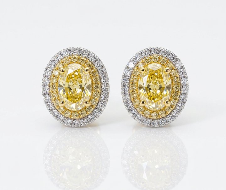 Fancy Vivid Yellow oval lab-grown diamond stud earrings with two-tone double pavé halos in 14K white and yellow gold — studio view