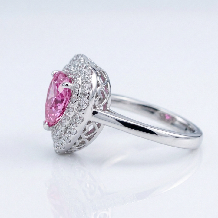 Side view of pink sapphire heart ring showing diamond pavé and heart filigree gallery in 14K white gold